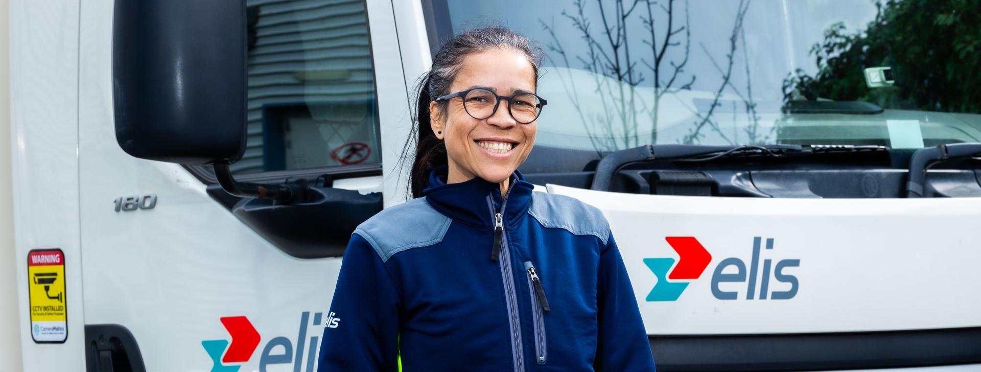 Woman driver standing beside a truck smiling