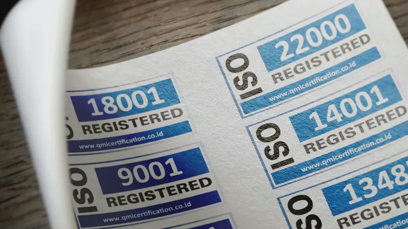 A sheet of blue and white ISO certification stickers on a wooden surface.