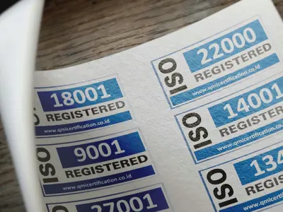 A sheet of blue and white ISO certification stickers on a wooden surface.